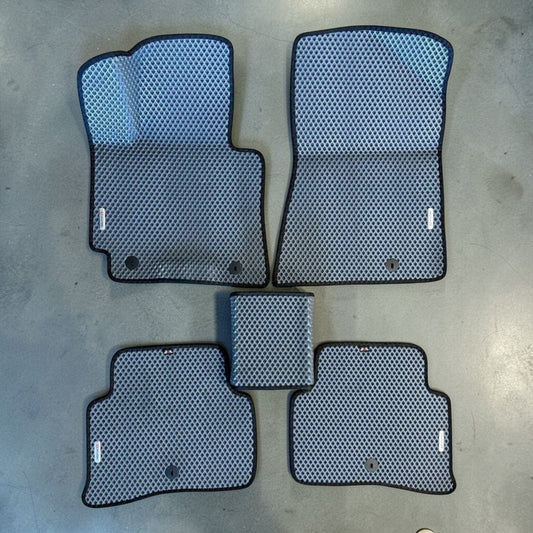 Set of car floor mats with a honeycomb pattern on a concrete floor.